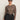 A woman wearing the Sanctuary Clothing long sleeve perfect mesh tee in French Kitty (extended sizing), black sunglasses, black belted pants, and hoop earrings stands confidently against a plain light background.