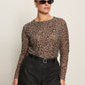 A woman wearing the Sanctuary Clothing long sleeve perfect mesh tee in French Kitty (extended sizing), black sunglasses, black belted pants, and hoop earrings stands confidently against a plain light background.