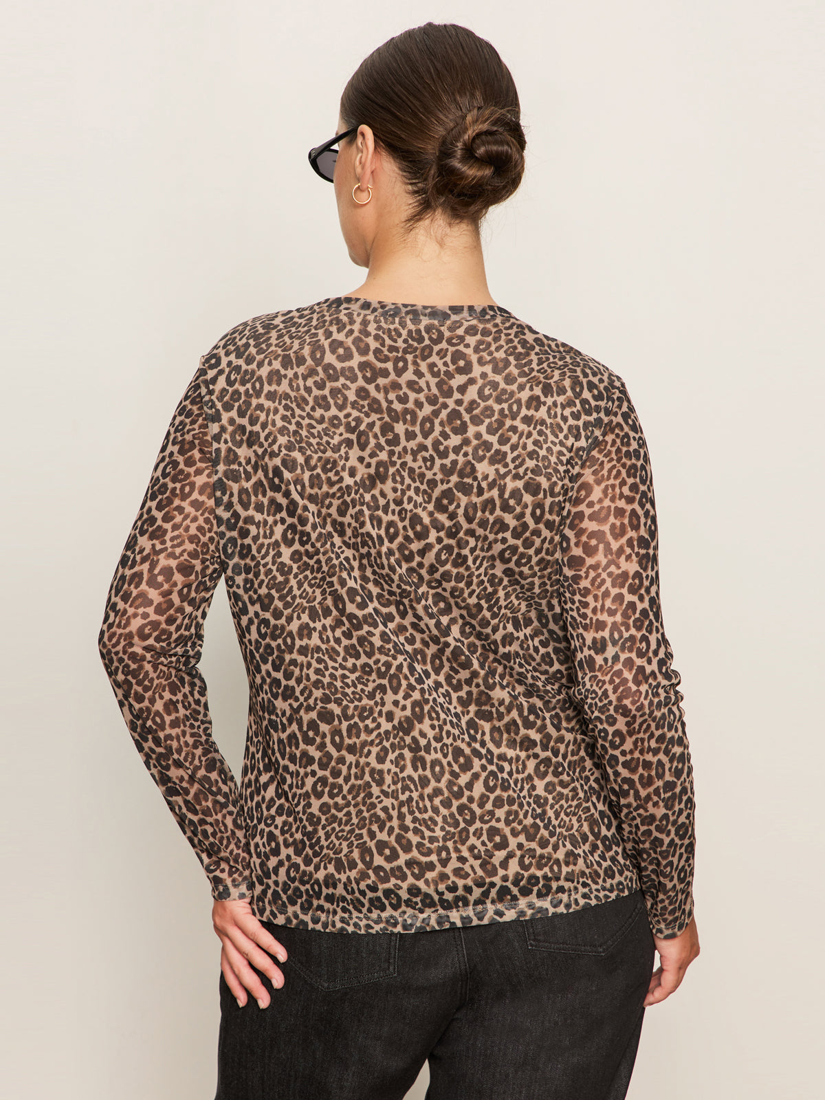 A person with their hair in a bun and glasses wears the Sanctuary Clothing long sleeve perfect mesh tee French Kitty (extended sizing), standing with their back to the camera against a plain light background.