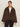 A woman with dark hair tied back wears the Sanctuary Clothing Colette Fur Jacket in Choco Chip (extended sizing) over a white sweater and dark pants, standing against a plain light background.