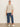 A woman stands against a plain light wall, wearing Sanctuary Clothing’s perfect sweater tee in heather pearl (extended sizing), blue wide-leg cropped jeans, and white sneakers. Her hair is pulled back and she looks at the camera with a relaxed posture.