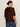 A woman with brown hair in a low bun wears Sanctuary Clothing's perfect sweater tee chicory (extended sizing) and blue jeans, standing turned away against a plain light background.