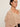 A woman with her hair in a low bun wears the Sanctuary Clothing "fade into you ruffle blouse" in fawn—a light beige, sheer blouse with ruffles, a V-neckline, and long, loose sleeves—while gazing to the side against a plain background.