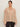 A woman wears the Sanctuary Clothing "fade into you ruffle blouse" in fawn—a loose, sheer beige top with ruffled shoulders and long sleeves—paired with dark pants against a light background.