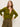 A woman with long brown hair wears an olive green button-up cardigan and high-waisted olive pants, posing with one hand on her hip against a plain light background.