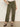 A person wears Sanctuary Clothing's boyfriend utility high rise pant in kalamata, styled with a light top and leopard print flats, standing against a plain background.