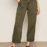 A person wears Sanctuary Clothing's boyfriend utility high rise pant in kalamata, styled with a light top and leopard print flats, standing against a plain background.