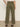 A person stands indoors, back facing camera, wearing Sanctuary Clothing™s boyfriend utility high rise pant in kalamata, paired with a light top and leopard print flats.
