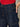 Close-up of a person wearing Sanctuary Clothing soleil 90s straight jeans in indigo dark raw rinse, featuring yellow stitching and their right hand in the front pocket, paired with a red textured top.