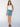 A woman with long hair stands against a plain background wearing a white tank, black sandals, and the Sanctuary Clothing "all buttoned up skirt dream team," with one hand in her skirt pocket.