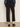 A person wearing Sanctuary Clothing's ponte barrel trouser in black, shown from the back indoors against a neutral background, styled with a dark blue long-sleeve blouse and black heeled mules.