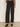 A person wearing Sanctuary Clothing's Charter Gab Barrel Pant in black, styled with a long-sleeve animal print blouse and black heeled mules, stands against a plain background.