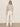 A person stands against a plain background wearing sunglasses, the Sanctuary Clothing perfect sweater tee in heather pearl, white high-waisted wide-leg pants, and white sneakers.