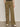 A person wearing Sanctuary Clothing’s cruiser full length pant in dirty martini, featuring wide legs and large front pockets, stands on a gray floor. Only the lower half and their white sneakers are visible.