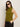 A woman wears the Sanctuary Clothing fuzzy shell martini olive sleeveless turtleneck sweater, paired with black pants and large black sunglasses, standing against a neutral background with one hand in her pocket.