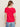 A woman with long brown hair, wearing sunglasses and the Sanctuary Clothing notch neck tee radiant in bright red with light blue jeans, stands with her back to the camera against a plain light background.