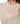 A close-up of a person wearing Sanctuary Clothing’s the ethereal blouse chalk—a sheer, white, long-sleeve top with a ruffled neckline and subtle polka dots. Their face is partially out of frame and one arm crosses their chest.