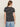 A person with long brown hair stands against an off-white background, wearing Sanctuary Clothing's the perfect tee white black stripe 5 and light blue jeans.