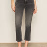 A person wearing Sanctuary Clothing astra kick crop jean in washed black denim, paired with a black top and black slip-on shoes, stands against a plain light-colored wall. The image is cropped to show only the lower half of the body.