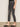 Someone wearing Sanctuary Clothing's astra kick crop jean in washed black denim and black slip-on shoes stands sideways against a plain wall.
