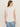 A woman with straight brown hair wears the Sanctuary Clothing side tie muscle tee in white and light blue jeans, standing with her back to the camera against a plain light background.
