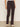 A person wears Sanctuary Clothing's corduroy hayden bootcut pant semi sweet petites in dark brown with front patch pockets, paired with a white top and light beige shoes, standing against a plain background.