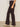 A person in Sanctuary Clothing's corduroy hayden bootcut pant semi sweet petites and light beige heeled boots stands sideways against a plain light-colored wall.