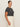 A woman with pulled-back hair and a neutral expression wears Sanctuary Clothing's "the perfect tee white black stripe 6"—a black and white striped short-sleeve shirt—tucked into high-waisted cream pants, standing in profile against a light background.