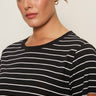 A woman with brown hair and gold hoop earrings confidently models the Sanctuary Clothing 'the perfect tee white black stripe 6'—a black T-shirt with white stripes—against a plain background.