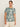 A woman with her hair pulled back and a neutral expression models Sanctuary Clothing's "the perfect tee green oasis extended sizing," a white short-sleeve shirt with a bold green leaf print, paired with light-colored pants against a plain background.