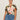 A woman with dark hair tied back wears Sanctuary Clothing’s the perfect tee reef vibes extended sizing, tucked into high-waisted blue jeans. She stands against a light background, looking confidently at the camera.