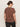 A person with dark hair in a low bun wears sunglasses and the Sanctuary Clothing perfect tee boheme extended sizing, a brown short-sleeve top with white floral pattern, and dark pants. They are facing away from the camera against a plain light background.
