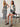 Two women in black-and-white stripes; one stands in a sleeveless knit maxi dress and sandals, the other sits wearing Sanctuary Clothing's mesh stitch shell sweater in black chalk stripe with a white tee, black shorts, and sandals.