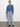 A woman models the Sanctuary Clothing tie front volume blouse in blue slate, paired with light blue jeans. Her dark hair is pulled back, and she completes the look with black shoes against a plain white background.