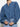A person is wearing Sanctuary Clothing's tie front volume blouse in blue slate, styled with light blue jeans. Their hands rest near the shirt's knot against a plain white background.