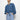 A person poses against a white background wearing the Sanctuary Clothing tie front volume blouse in blue slate and light blue jeans, with their hands in their pockets, looking forward.