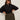 A woman wearing dark sunglasses and the Sanctuary Clothing petal drop blouse black extended sizing stands with her hands on her hips, paired with high-waisted olive green pants against a plain light background.