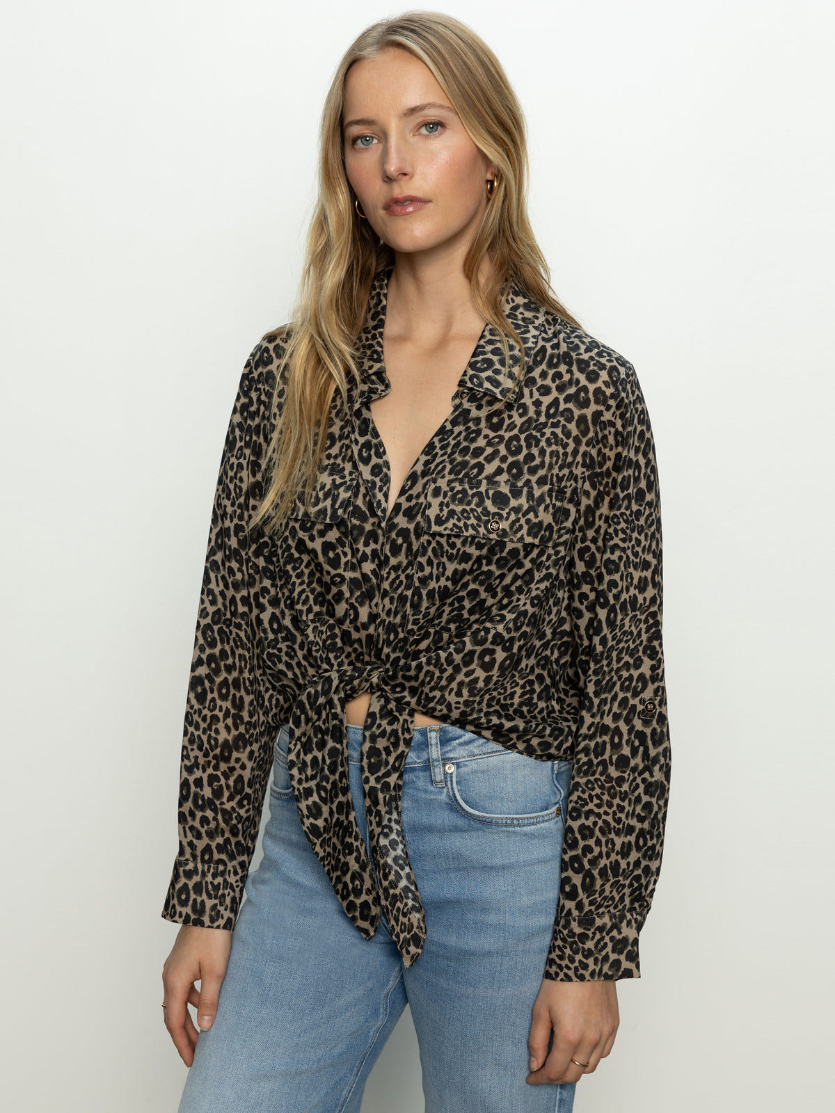 A woman with long blonde hair models the "wild love tie top french kitty" by Sanctuary Clothing, a leopard-print blouse tied at the waist, paired with light blue jeans against a plain white background.