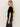 A woman with long blonde hair stands in profile against a plain light background, wearing the Sanctuary Clothing "we belong together" black velvet top and dark high-waisted jeans.
