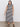 A person poses confidently in Sanctuary Clothing's contrast trim maxi dress in black macrame stripe, extended sizing, featuring side slits and paired with black sandals against a plain light-colored wall and floor.