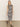 A person with long hair is wearing the contrast trim maxi dress in black macramé stripe by Sanctuary Clothing and black sandals. They stand on a plain floor against a neutral background.
