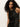 A woman with long, curly dark hair wears the Sanctuary Clothing "everyday satin dress black olive" and stands against a plain light background, looking directly at the camera with a neutral expression.