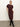 A woman poses against a plain light background, wearing the Sanctuary Clothing cinched waist t shirt dress in chicory, styled with black knee-high boots. She stands with one leg crossed and a hand on her hip.