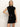 A woman poses against a plain light background in the Sanctuary Clothing "an affair to remember dress black," a sleeveless, high-neck sequin mini dress, with one hand on her hip.