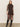 A woman poses against a plain light background in the Sanctuary Clothing night out mock sweater dress semi sweet, a fitted black dress with three-quarter sleeves and side slit, paired with knee-high black boots.