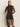 A woman models the Sanctuary Clothing night out mock sweater dress semi sweet, a sheer, fitted black piece with long sleeves, high neckline, and a side slit; she stands against a plain background with hands behind her back.