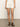 Someone in a white shirt and Sanctuary Clothing's arden denim short bleached white pinstripe stands on a smooth surface, wearing black strappy sandals. The image highlights the lower body against a neutral background.