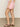 Someone wearing a white top, Sanctuary Clothing's arden denim short in washed cherry blossom, and brown sandals stands on a concrete floor. The focus is on the shorts, shown from the side.