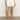 A person wearing a green top and Sanctuary Clothing's flower field short in bleached white with a tie belt stands on a beige floor, donning brown strappy sandals and casually keeping one hand in the pocket of their shorts.