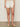 A person wears Sanctuary Clothing's voyage short in bleached white with a white textured top and beige woven sandals, standing against a plain background with their hands relaxed by their sides.